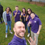 Team members pose for a photo with their hands in the shape of a W for UW.