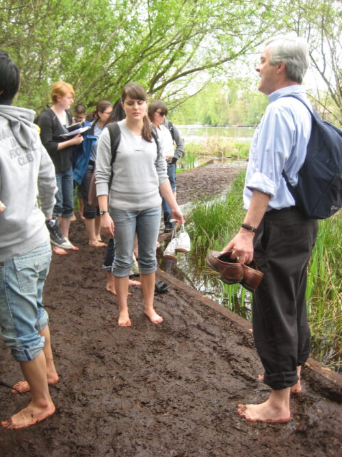 Iain and students in a park barefoot standing in mud