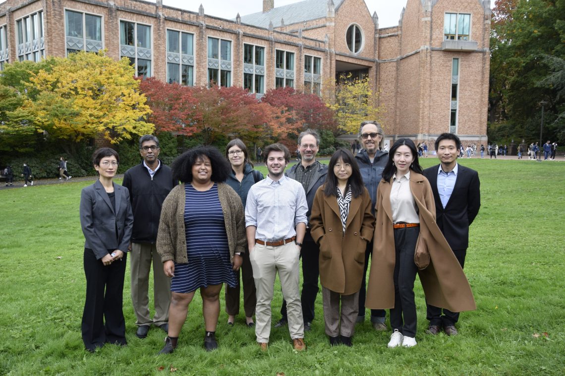 Students and faculty standing in the grass in front of a brick building