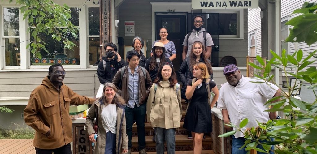 Students, faculty, and community members standing on the front porch of a house that houses Wa Na Wari