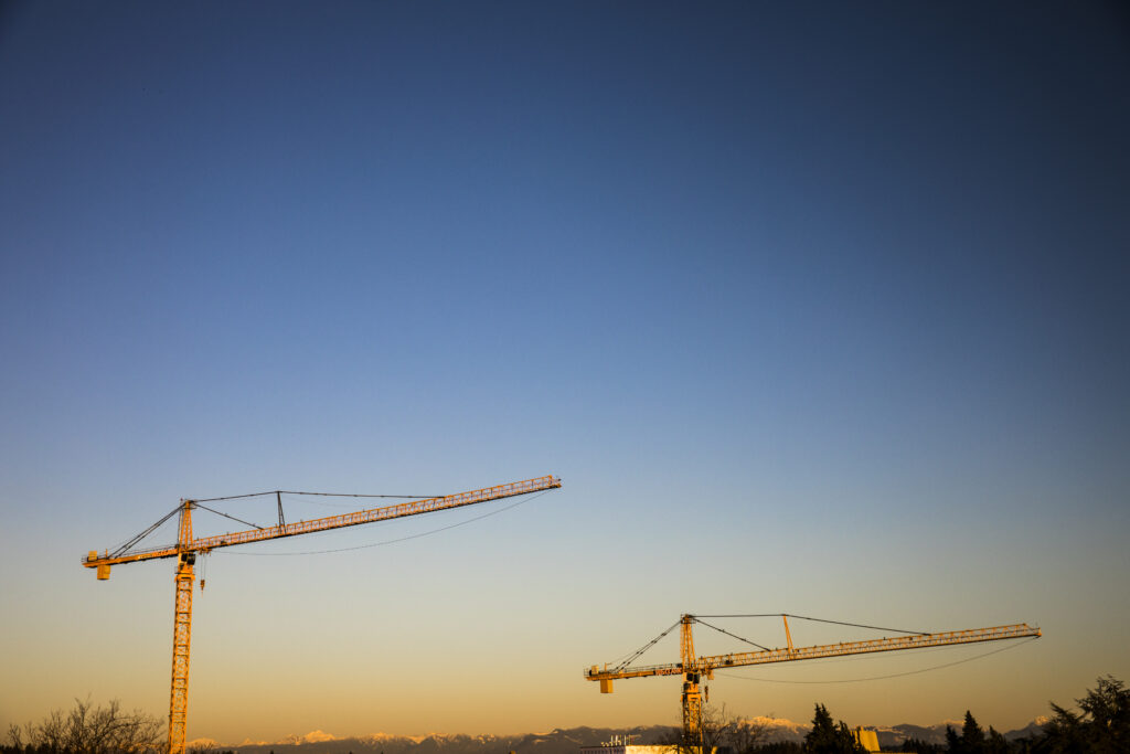 Two yellow cranes stand against an evening sky