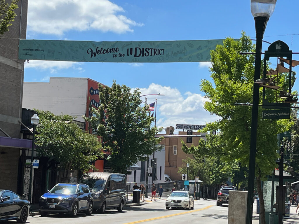 A sign hanging over the street that says Welcome to the U District