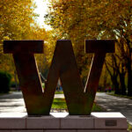 Bronze block W that stands at entrance to UW on NE 45th Street. In background is Memorial Way. Fall.