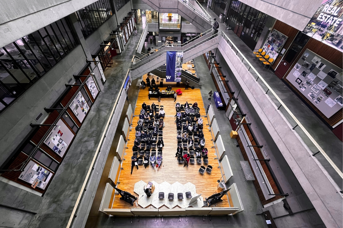 Wide view of Gould Hall, with a group of people sitting in rows in Gould Court for a lecture.