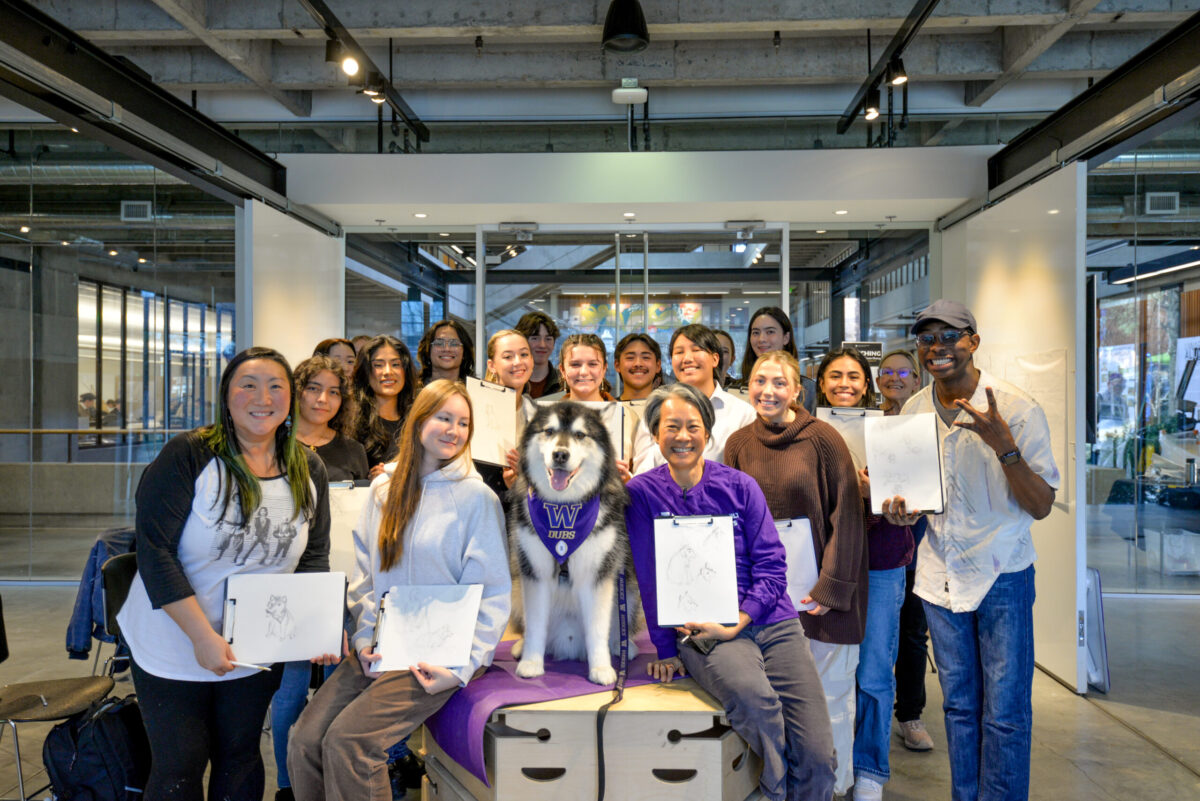 Group of students smiling and holding up sketches with Dean Cheng and Dubs