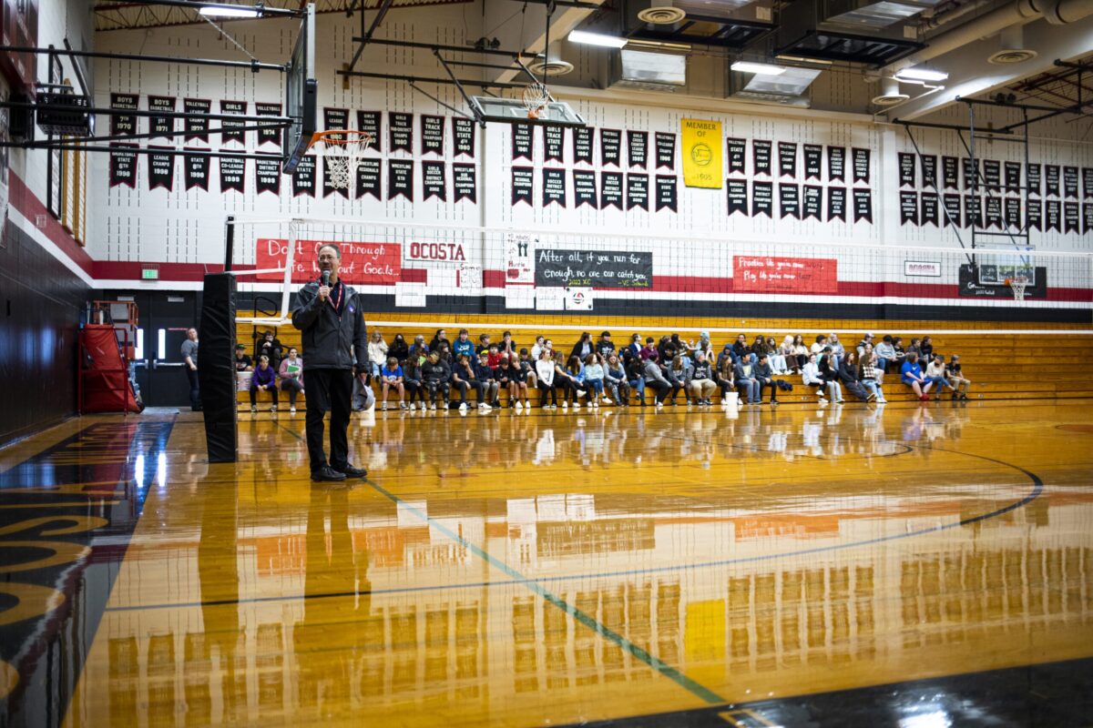 Dan Abramson speaking to a crowd in a high school gymnasium