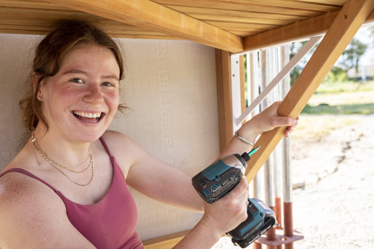 Student with a drill smiling and looking at viewer