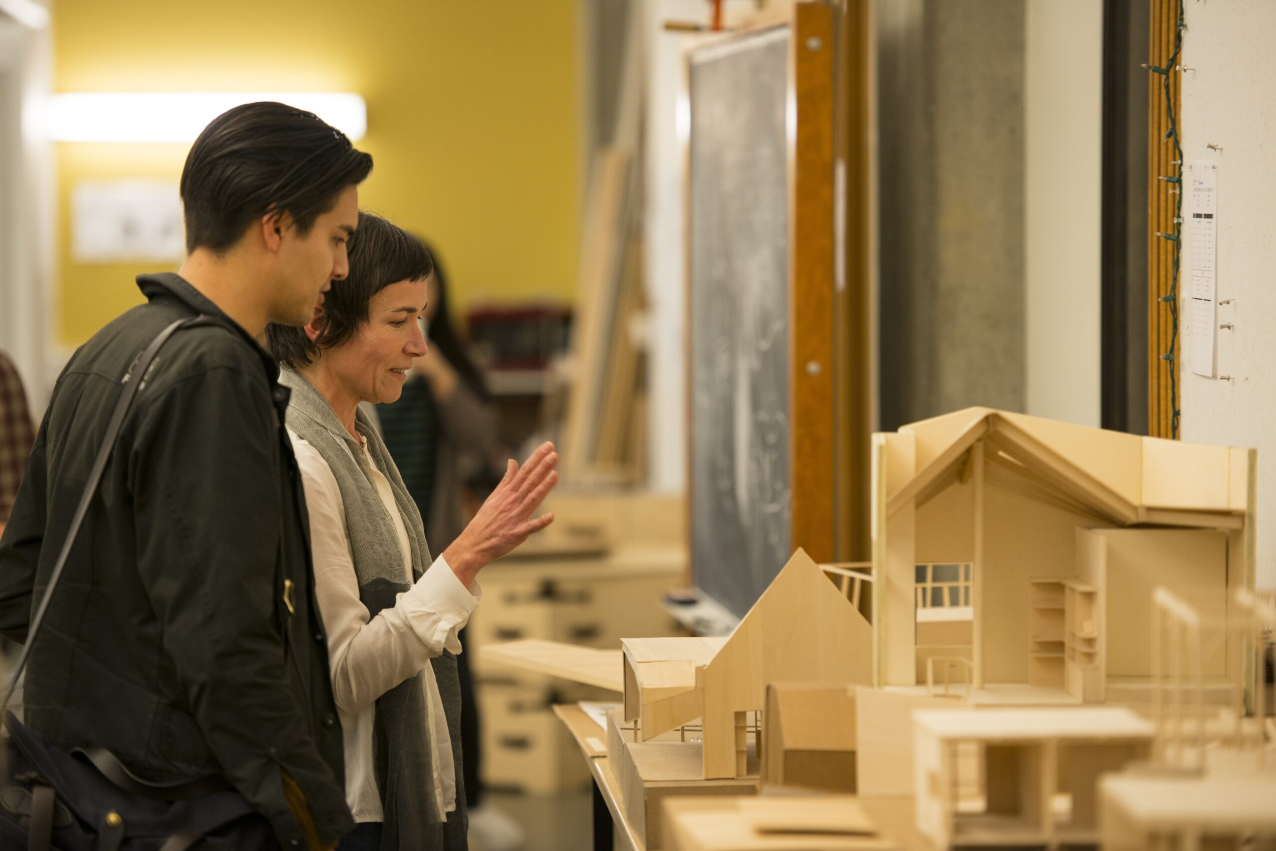 Two people looking at wooden models of houses