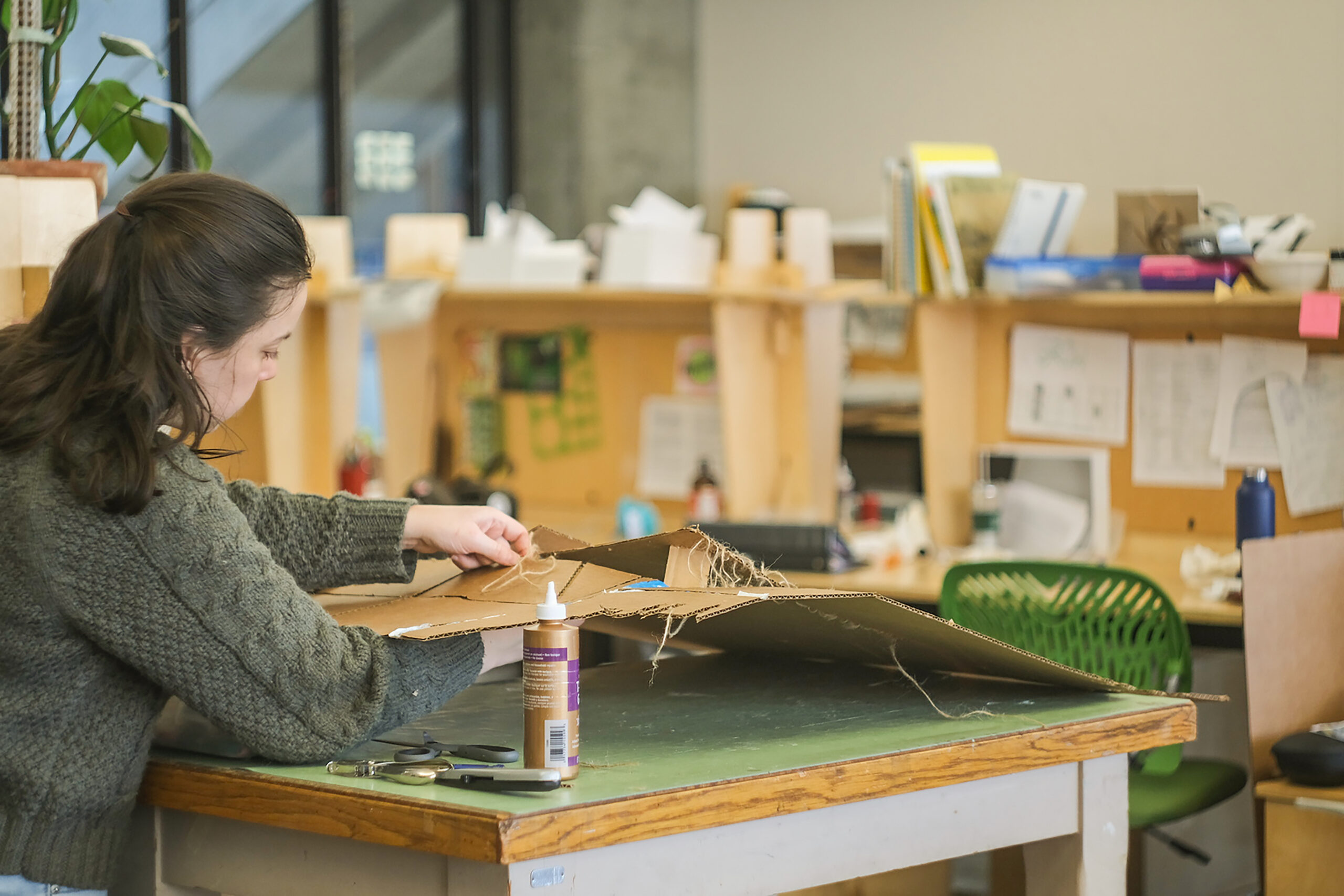 Student cutting cardboard on a cutting mat for their architecture project