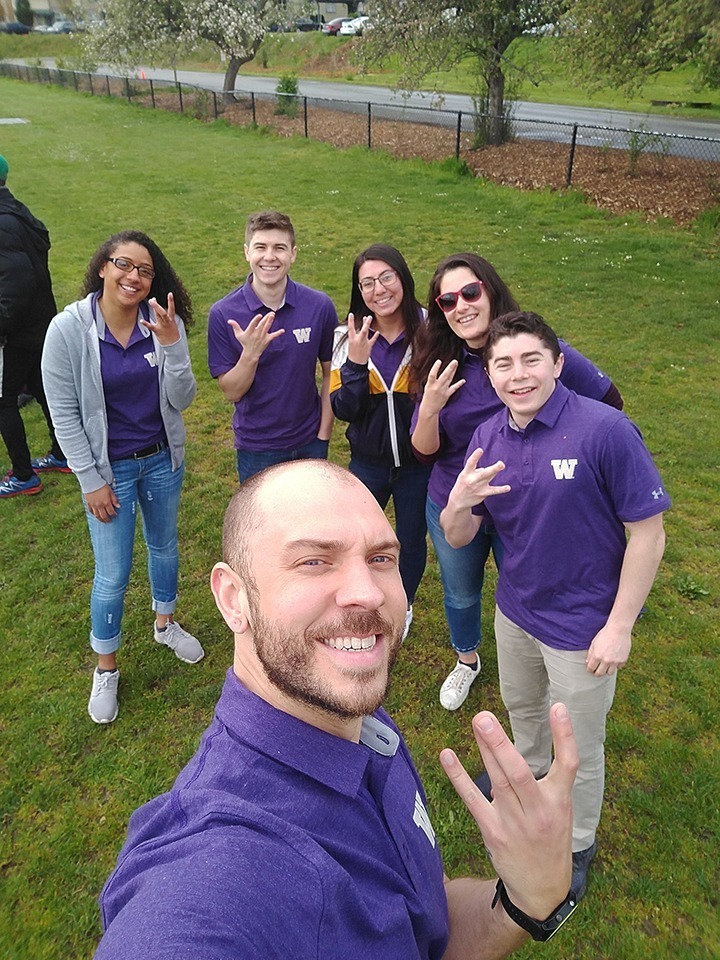 Team members pose for a photo with their hands in the shape of a W for UW.