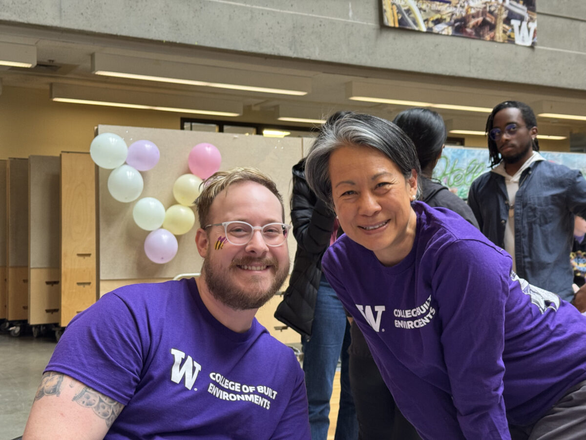 Two people smiling, one with face paint on their cheek