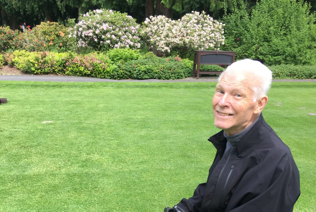 Dr. Bob sitting on a bench on a golf course