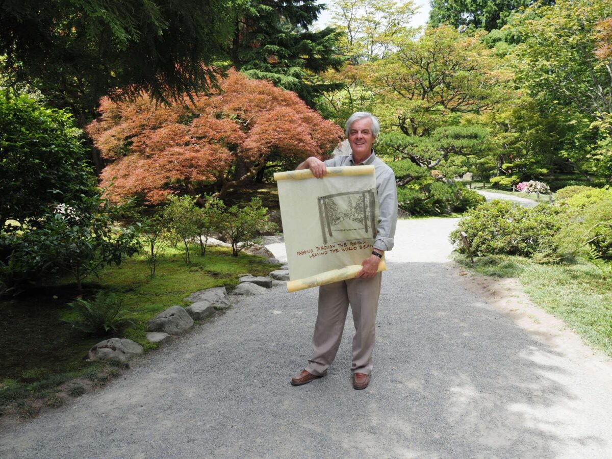 Iain Robertson standing in the Seattle Japanese Garden holding a scroll