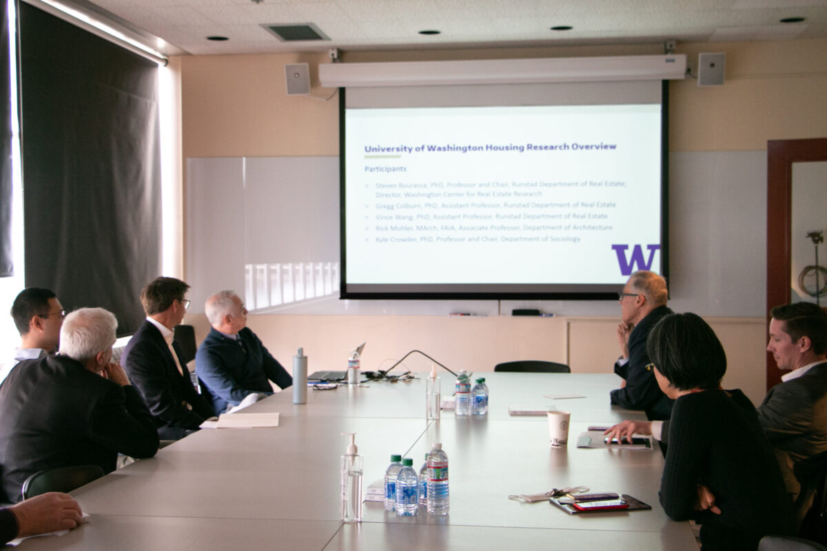 People sitting around a table looking at a projector screen