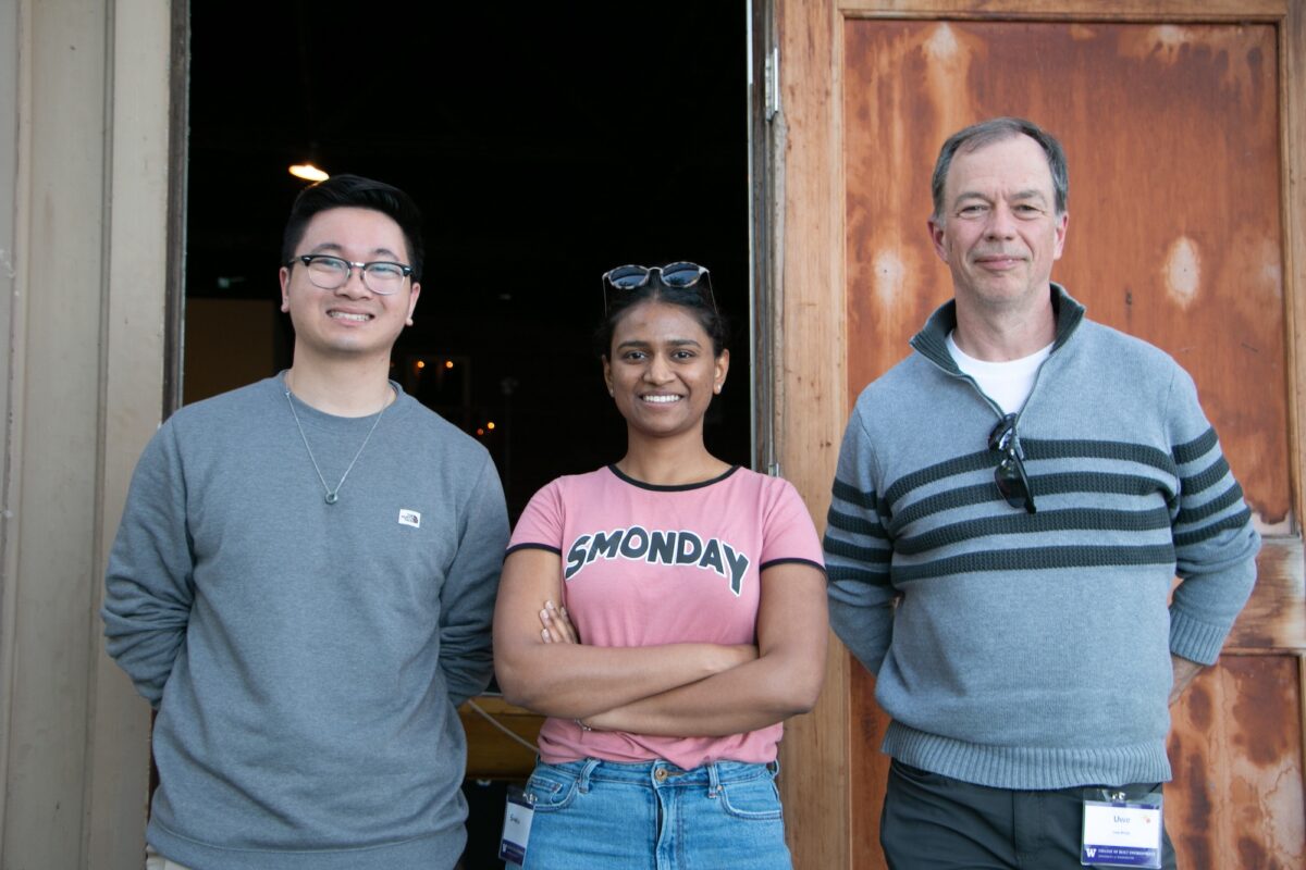 Two students and a mentor standing and smiling at the camera