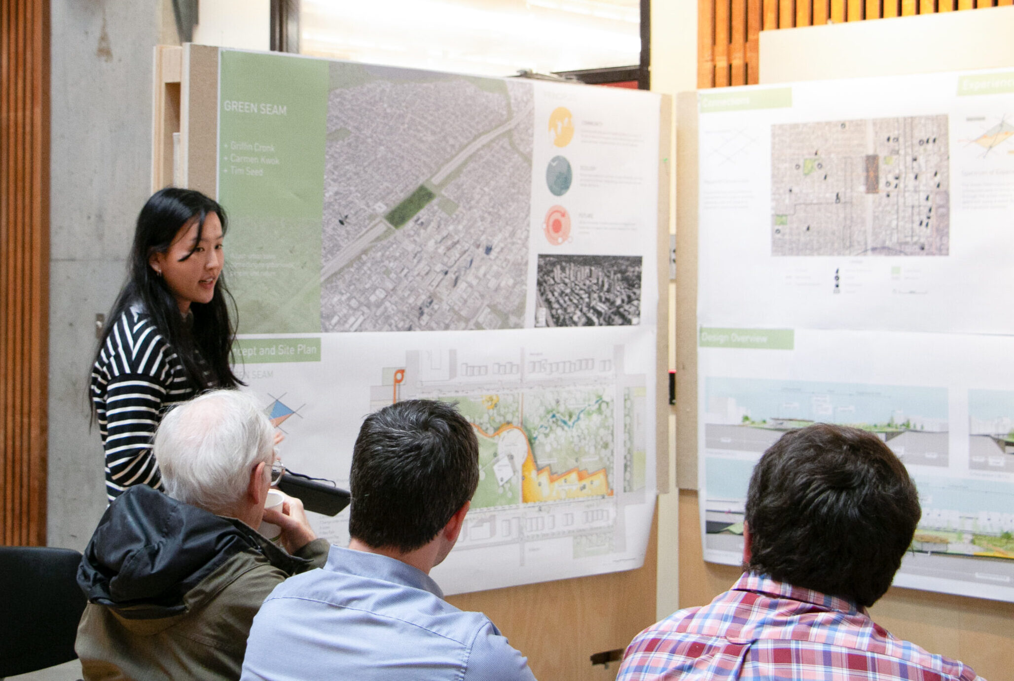 Student presenting urban design project on posters in front of an audience.