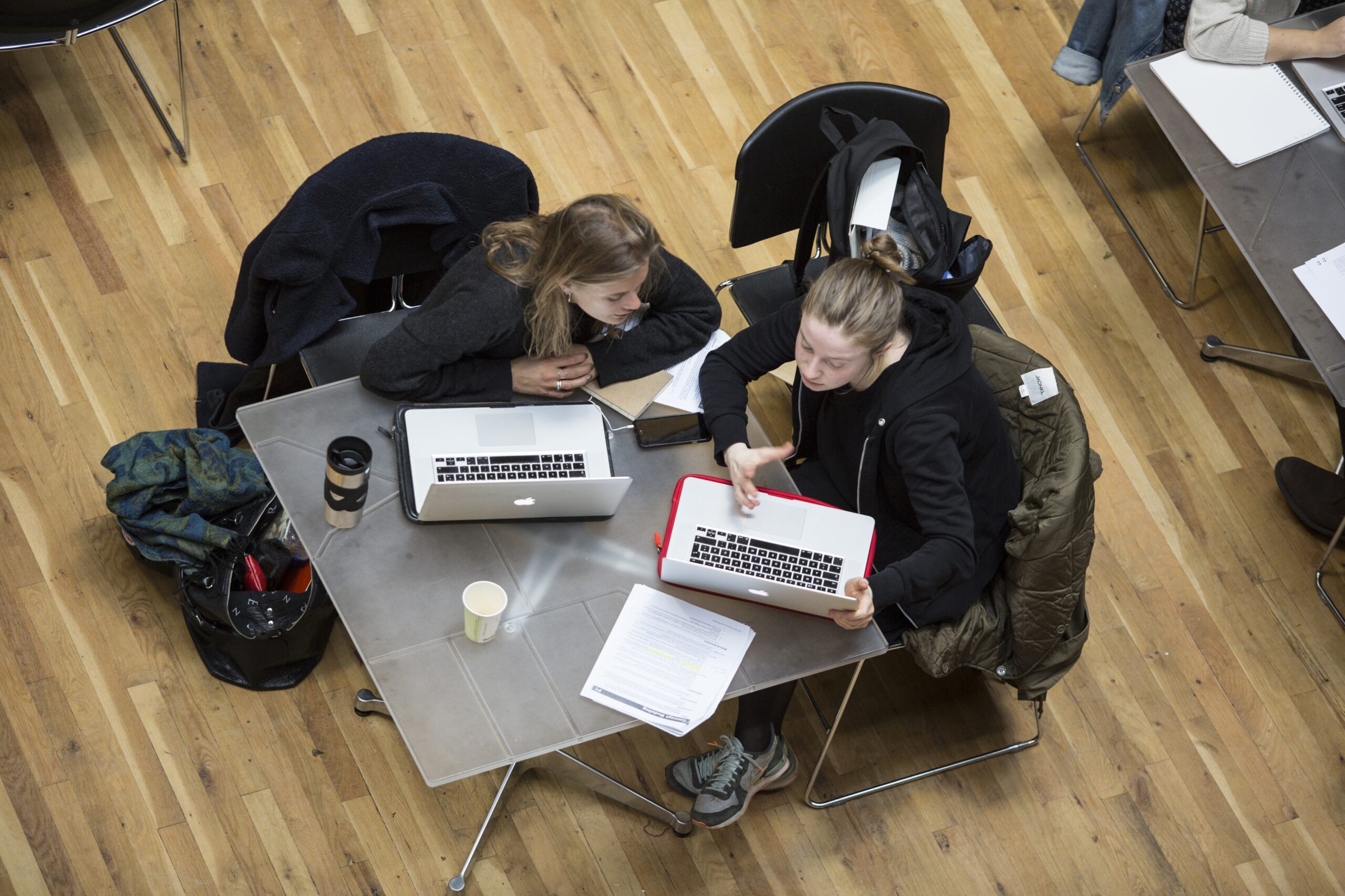 Two students working on their computers at a table
