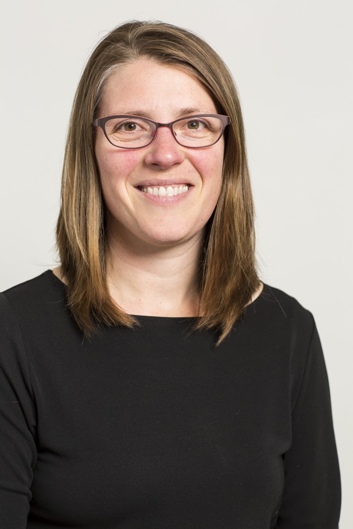 Headshot of Carrie Sturts Dossick in a black shirt wearing glasses