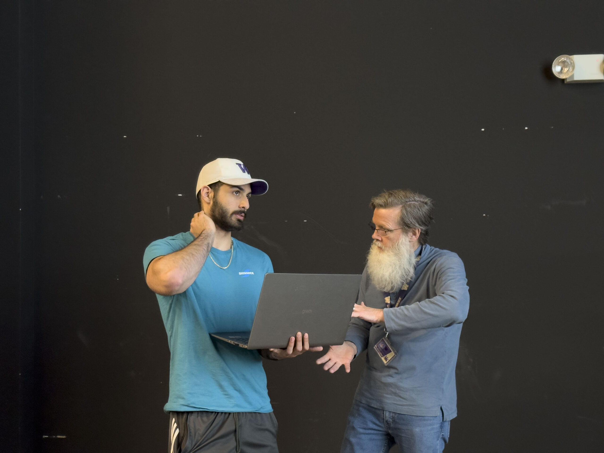 Student holding computer and talking to a professor
