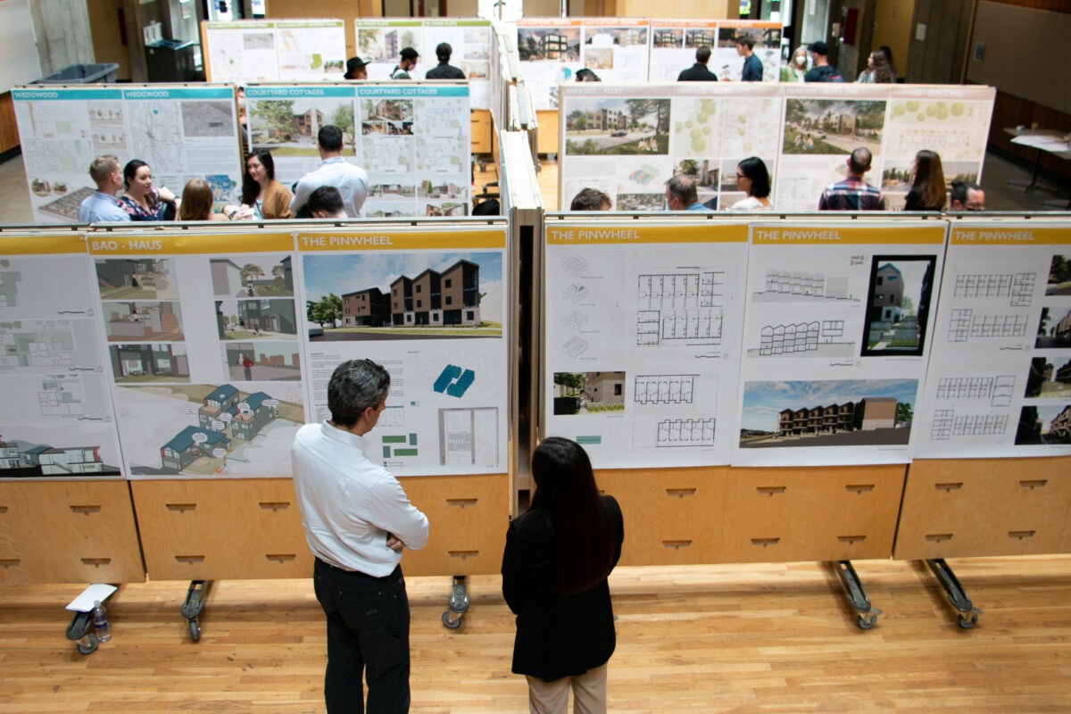 Rows of posters on wooden boards with people looking at them