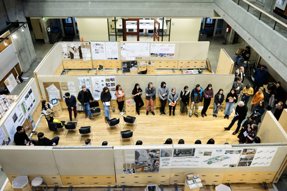 Students gathered in a circle surrounded by posters of projects