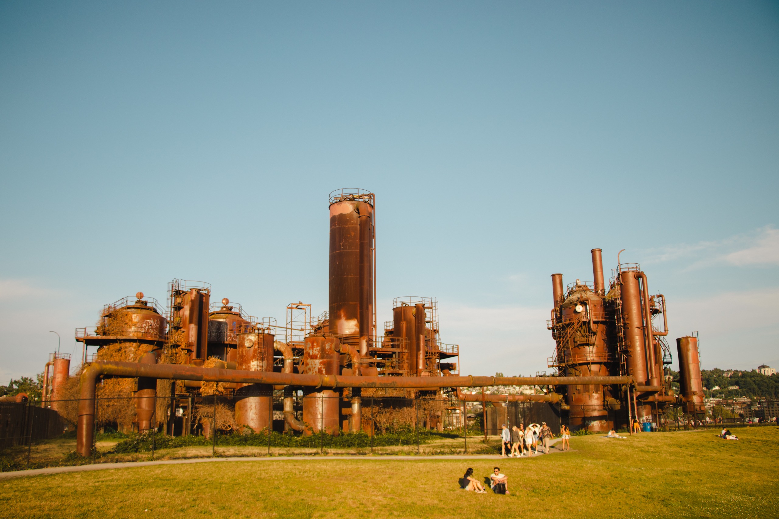 Large metal structures in a field of grass with people sitting and talking.