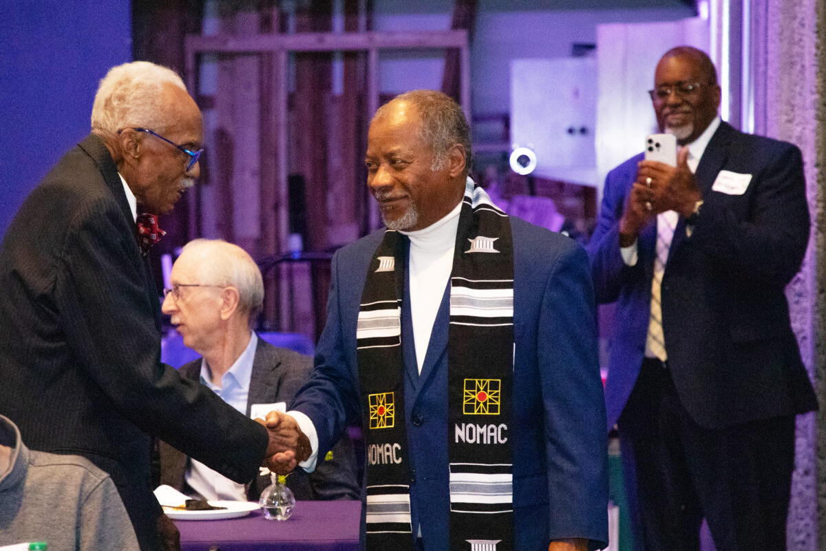 Two men shaking hands in a crowd of people