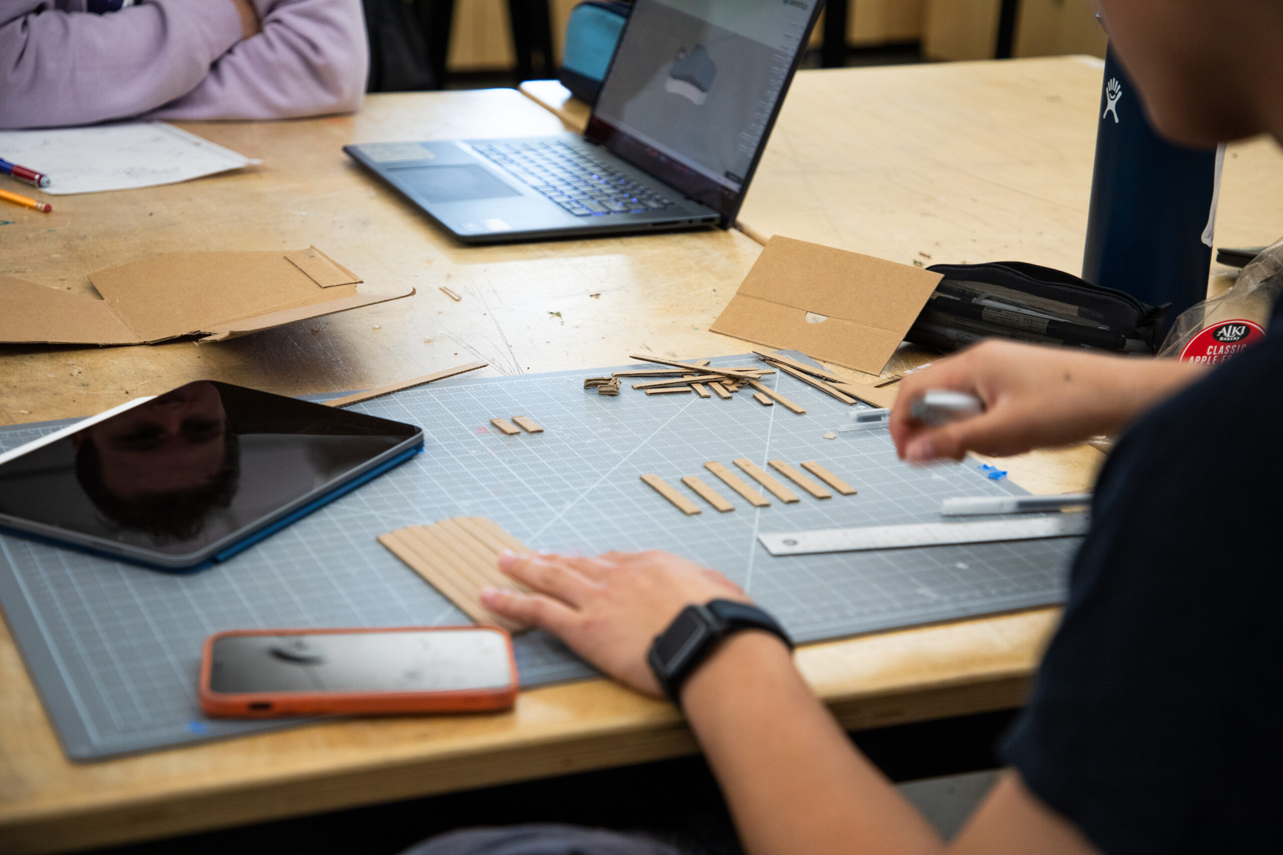 Student cutting cardboard into thin strips
