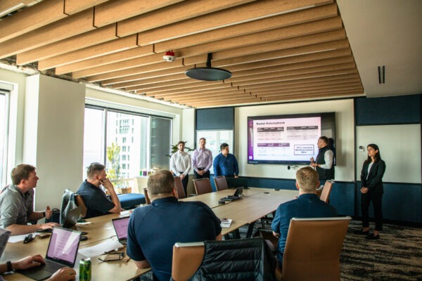 Students presenting in a room full of people around a table