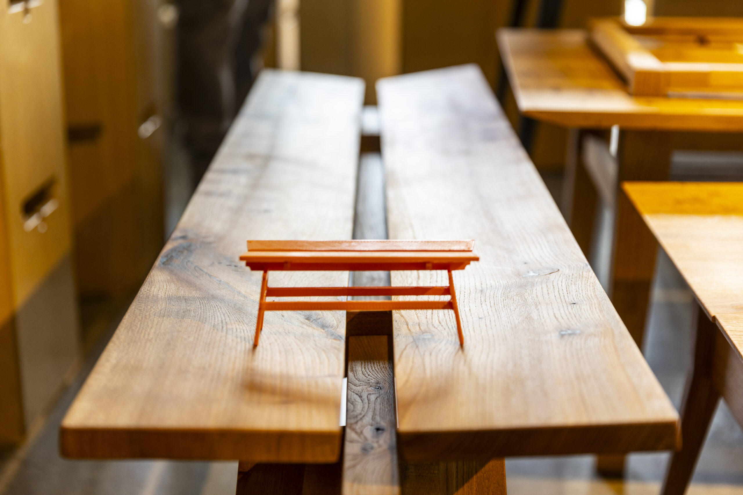 Student presents a handmade wood furniture piece during the final Furniture Studio review in the CBE Fabrication Lab.