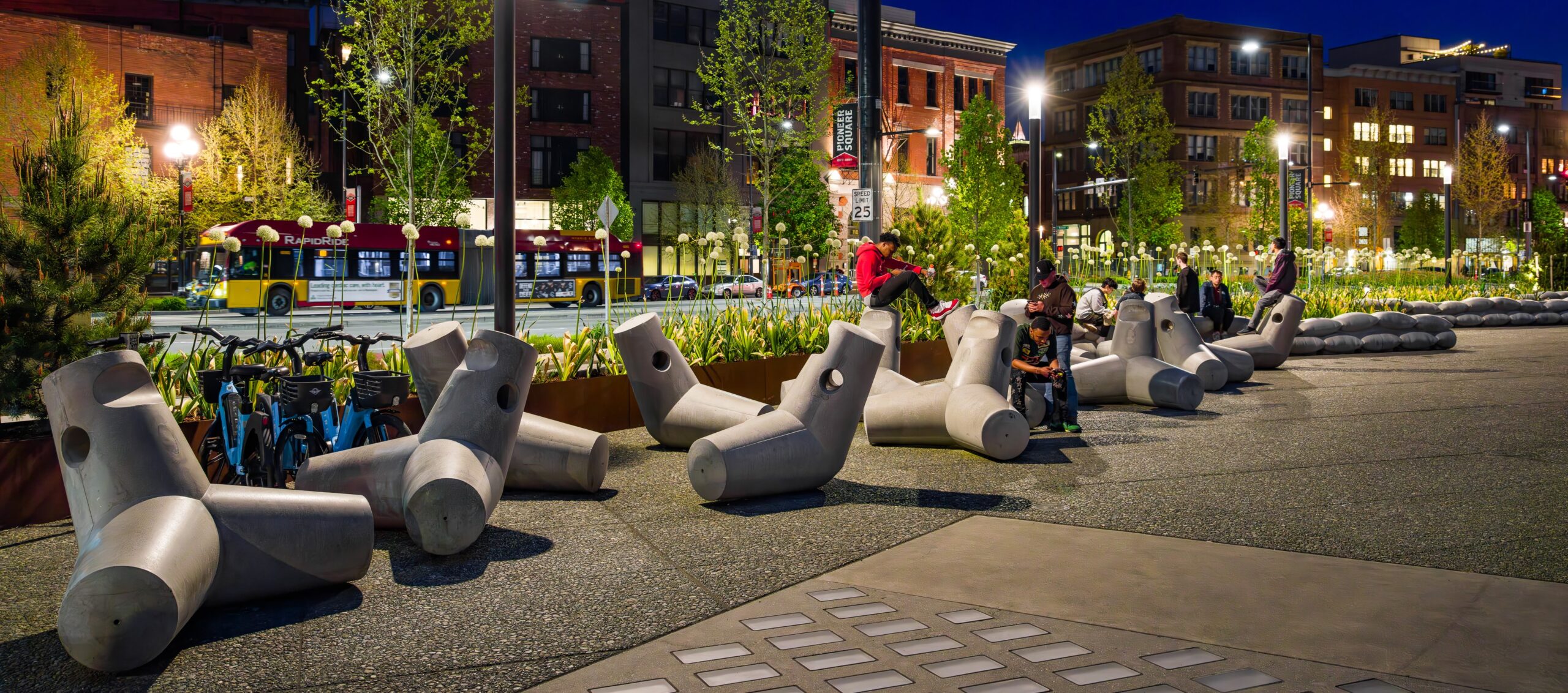 Concrete figures along a walkway at night