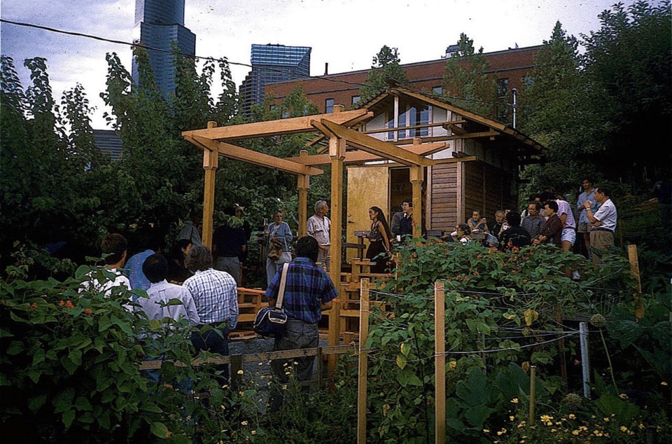 Group of people around a wooden structure in a garden