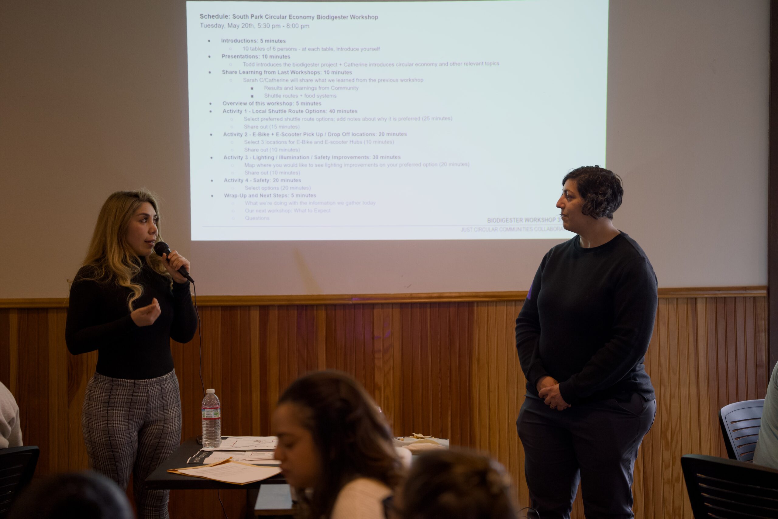 Two people presenting in front of a screen