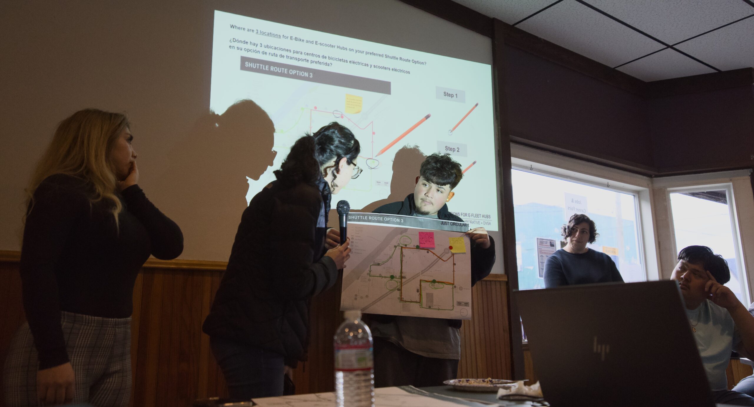 Two people present a route map to a room of people