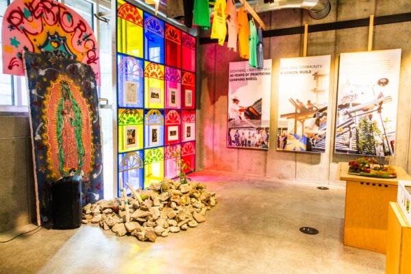 Brightly lit room with rocks on the ground and posters on the wall. Colorful light is coming through the windows