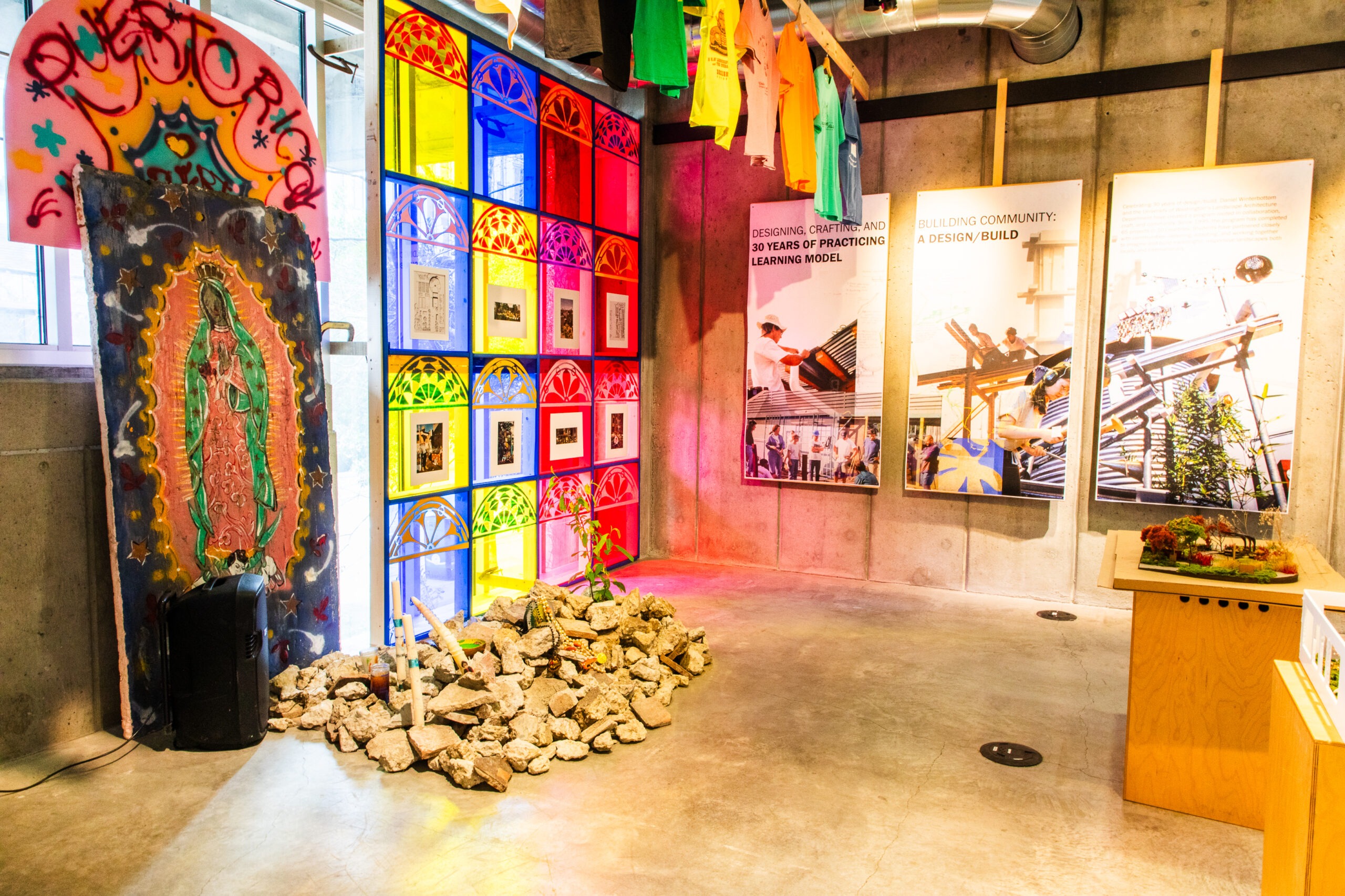 Brightly lit room with rocks on the ground and posters on the wall. Colorful light is coming through the windows
