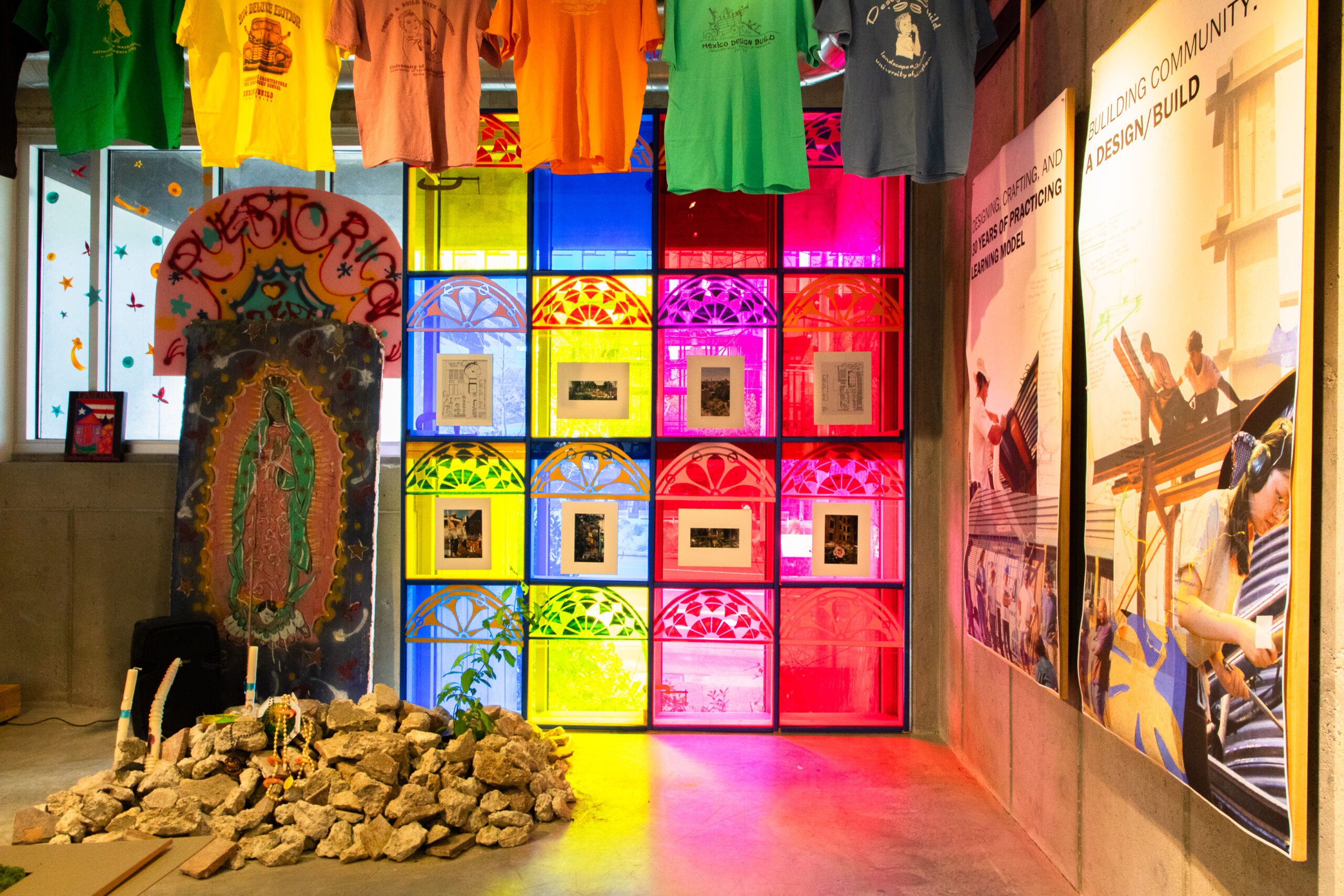 Brightly lit room with rocks on the ground and posters on the wall. Colorful light is coming through the windows