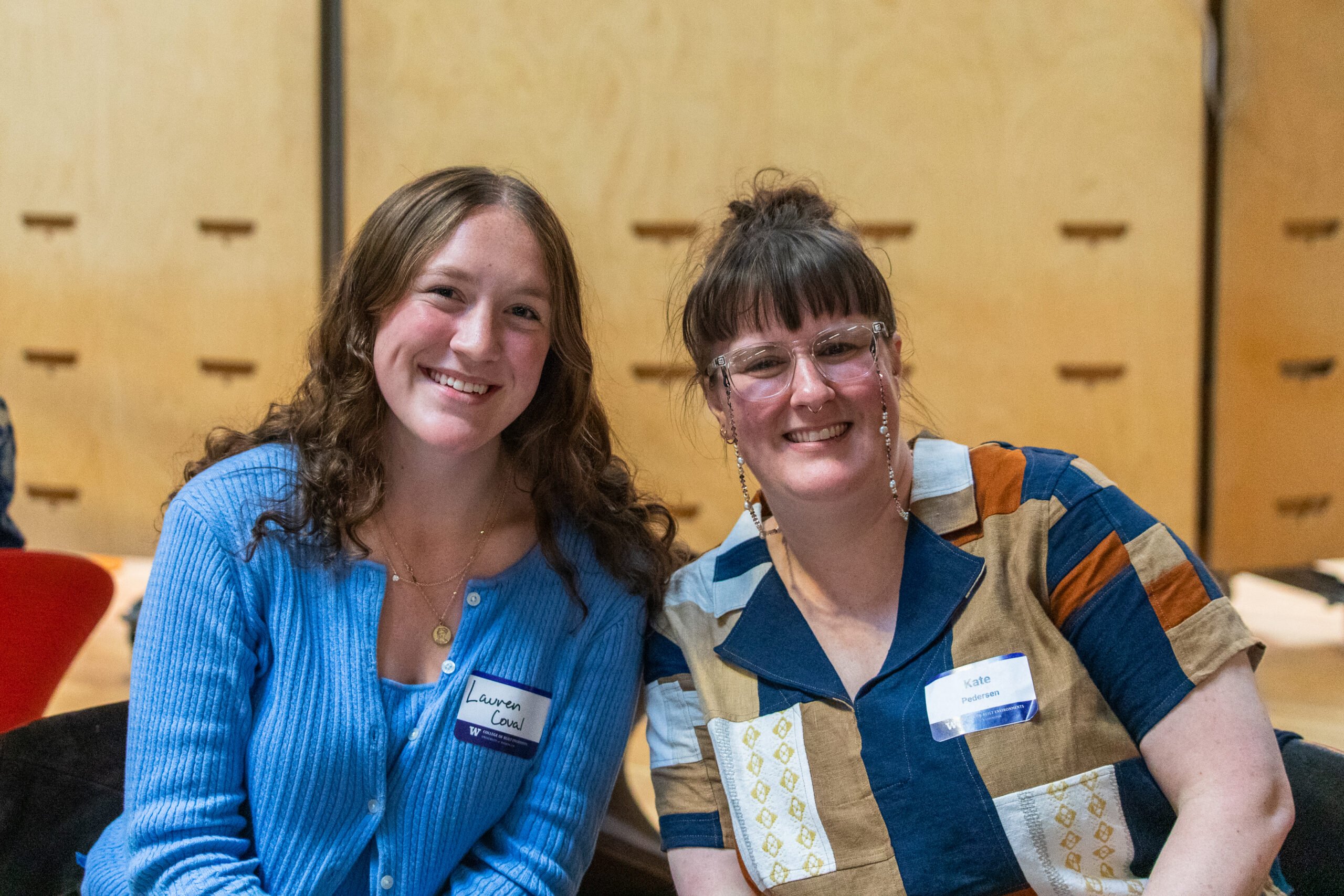 Two attendees seated together and smiling at the FrameWorks exhibition reception in Gould Hall.