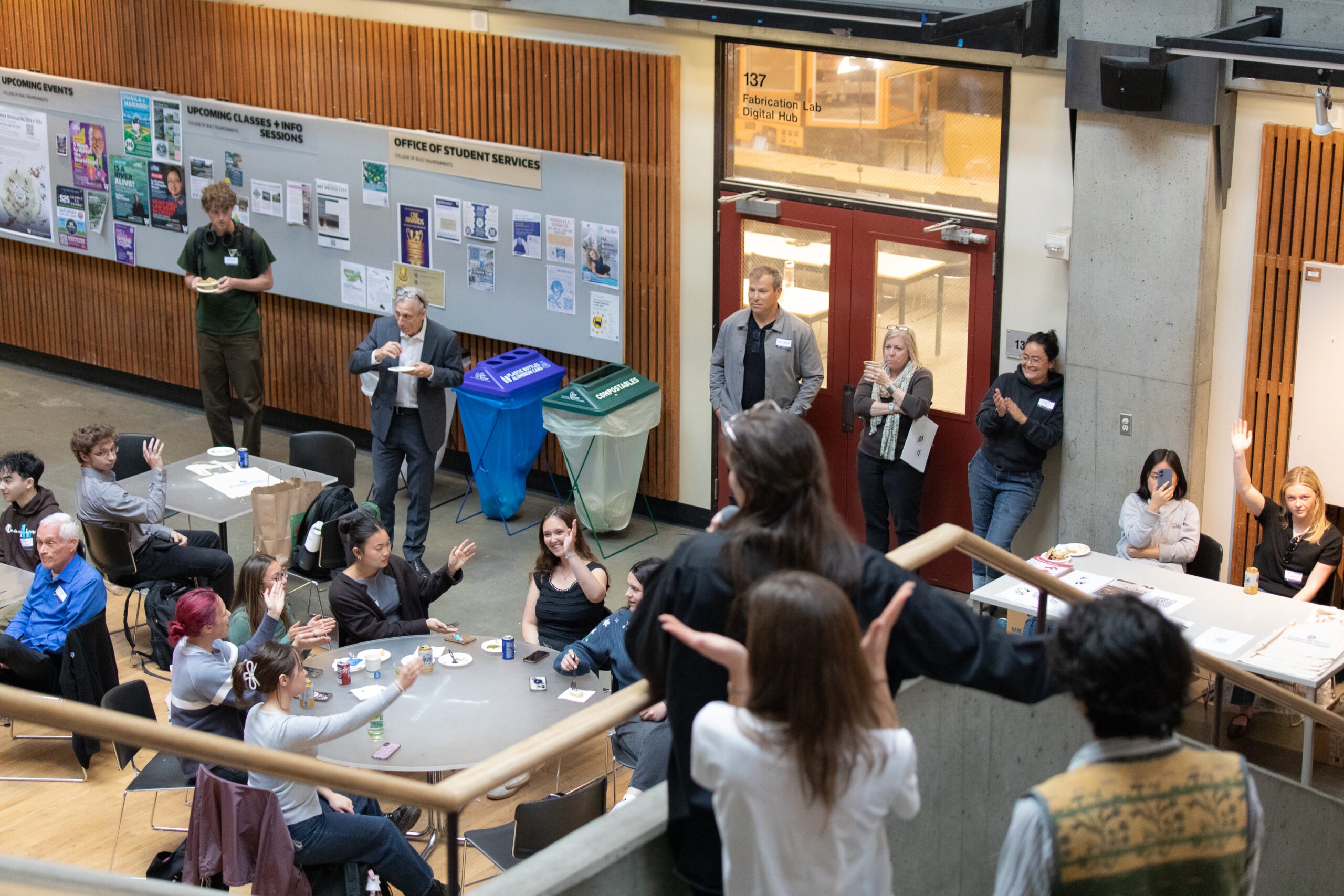 Attendees seated and standing throughout Gould Hall listen during a presentation at the FrameWorks exhibition reception.